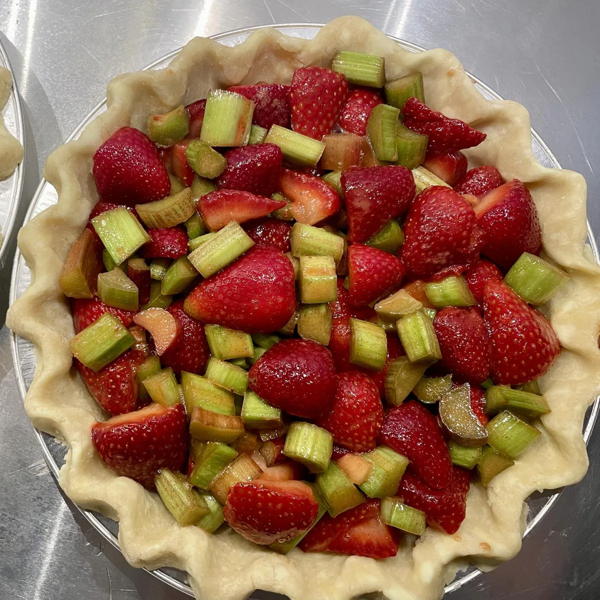 Strawberry rhubarb pie with a crimped crust, ready for the oven